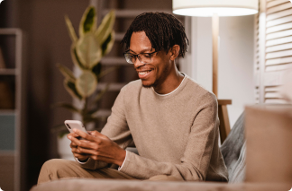 Homem com moletom bege, sorrindo e segurando o celular